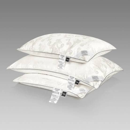 Stack of three infinity pillows showing the jacquard fabric pattern and care label detail